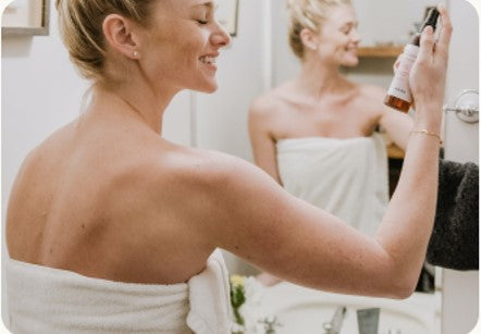 woman spritzing her skin as she enjoys a sip and spa experience